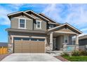 Inviting two-story home displaying a covered porch, two-car garage, and nicely landscaped front yard at 1043 High Point Trl, Elizabeth, CO 80107