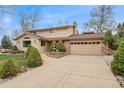 Wide driveway leading to a two-car garage and beautifully landscaped front yard with mature trees at 7106 S Kendall Blvd, Littleton, CO 80128