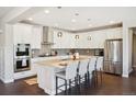 Modern kitchen featuring white cabinetry, granite countertops, stainless steel appliances, and island seating at 17829 W 95Th Pl, Arvada, CO 80007
