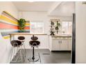 Compact kitchen featuring a breakfast bar, modern stools, and a vibrant accent wall design at 2774 W Irvington Pl, Denver, CO 80219