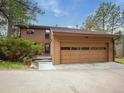 Side view of a well-maintained home showcasing an oversized attached two-car garage with a modern glass door design at 4198 Timbervale Dr, Evergreen, CO 80439