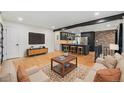 Open-concept living room with hardwood floors, a brick wall accent, and a modern kitchen view at 1111 Monroe St, Denver, CO 80206
