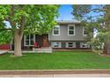 Beautiful two-story home with a well-manicured lawn, brick accents, and inviting front porch with a red chair at 8764 W 95Th Ave, Broomfield, CO 80021