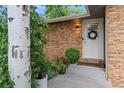 Inviting front porch with brick facade, potted plants, and a decorative wreath on the front door at 1746 Shavano St, Longmont, CO 80504