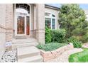 Inviting front entrance with brick accents, a well-maintained garden bed, and a decorative front door at 10565 Kalahari Ct, Lone Tree, CO 80124