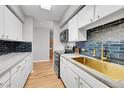 Modern kitchen with white cabinets, gold fixtures, and dark tile backsplash at 1020 15Th St # 27E, Denver, CO 80202