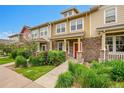 Townhome with manicured lawn, stone accents, colorful shrubbery and inviting red front door at 22801 E Briarwood Pl, Aurora, CO 80016