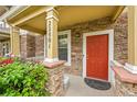 Close-up of charming front porch with stone pillars and a vibrant red front door at 22801 E Briarwood Pl, Aurora, CO 80016