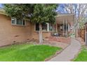 Inviting brick home with mature landscaping and a cozy front porch, perfect for enjoying the outdoors at 3667 Hudson St, Denver, CO 80207