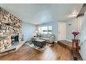 Comfortable living room with hardwood floors, a stone fireplace, and natural light from a large window at 68 S Moline St, Aurora, CO 80012