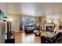 Cozy living room featuring hardwood floors, a fireplace, comfortable seating, and a view of the snow-covered outdoors at 1150 W 127Th Ct, Denver, CO 80234