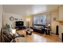 Inviting living room with hardwood floors, comfortable leather seating, and a large window overlooking a snowy scene at 1150 W 127Th Ct, Denver, CO 80234