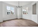 Bright dining area featuring hardwood floors, a modern chandelier, and windows at 8230 Snake River St, Littleton, CO 80125