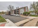 View of the apartment with parking lot and landscape trees and bushes at 6388 Oak Ct # 203, Arvada, CO 80004