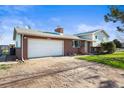Brick and Vinyl home featuring a spacious garage, long driveway and well manicured lawn at 29881 E 128Th Ave, Commerce City, CO 80022