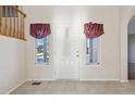 Inviting entryway with a white door flanked by windows, tile flooring, and staircase visible in the background at 2660 Timberchase Trl, Highlands Ranch, CO 80126