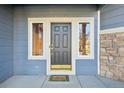The front entryway features a dark wood door, a welcome mat, two side windows and stone accents at 2660 Timberchase Trl, Highlands Ranch, CO 80126