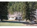 View of the home with mature trees, a cozy deck, and attractive landscaping in a serene wooded setting at 10039 S Turkey Creek Rd, Morrison, CO 80465