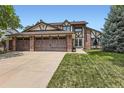 Two-story Tudor style home with a three car garage, brick accents, and well maintained lawn at 7863 W Friend Dr, Littleton, CO 80128