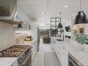 Modern kitchen featuring stainless steel appliances, white cabinetry, marble countertops, and open access to living spaces at 4432 Umatilla St, Denver, CO 80211