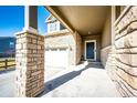 Close-up of stone-accented home exterior featuring a covered porch, front door, and attached garage at 469 S Olathe St, Aurora, CO 80017