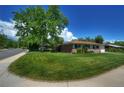 Classic ranch-style house featuring a brick facade, manicured lawn, mature tree, and a paved walkway at 855 33Rd St, Boulder, CO 80303