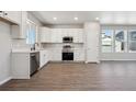 Bright kitchen featuring white cabinets, stainless appliances, and wood-look floors at 2263 Serenidad St, Brighton, CO 80601