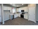 Modern kitchen featuring white cabinets, stainless steel appliances and gray wood flooring at 2263 Serenidad St, Brighton, CO 80601