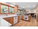 Bright kitchen with natural wood cabinets, hardwood floors, and an adjacent living area at 7351 S Sheridan Ct, Littleton, CO 80128