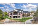 Expansive brick home with a deck, lush lawn, mature trees, and a driveway winding through a gated entrance at 3 White Pelican Cir, Thornton, CO 80241
