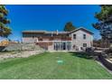 A spacious backyard featuring a manicured lawn, mature landscaping, a large deck, and a walkout basement at 7605 Shenandoah Dr, Elizabeth, CO 80107