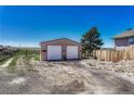 Detached two-car garage featuring two roll up doors and ample parking space on a gravel driveway, on a sunny day at 7605 Shenandoah Dr, Elizabeth, CO 80107