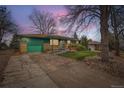 Ranch home at twilight featuring a well-kept lawn, rock garden, attached garage, and a ramp at 13621 E Center Ave, Aurora, CO 80012