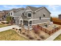 Beautiful home featuring stone accents, a charming porch, and a well-maintained side yard with landscaping at 16857 W 87Th Ave, Arvada, CO 80007