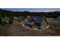 Aerial shot of a house with a detached garage, surrounded by a forest and mountains, offers privacy at 8191 S Homesteader Dr, Morrison, CO 80465