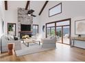 Bright living room with vaulted ceilings, stone fireplace, modern furnishings, and a sliding glass door leading to a deck at 526 N Fuller Placer Rd, Breckenridge, CO 80424