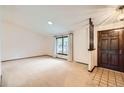 Bright living room features a large window, neutral carpet, and a dark wood front door with tile entry at 2556 S Eagle Cir, Aurora, CO 80014