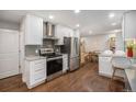 Modern kitchen featuring stainless steel appliances, granite countertops, white cabinets, and hardwood floors at 8299 E Kenyon Ave, Denver, CO 80237