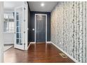 Inviting entryway featuring hardwood floors, a dark accent wall, and decorative birch-themed wallpaper at 3438 Cade Ct, Castle Rock, CO 80104