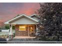 Charming home with stone accents and an inviting front porch, illuminated by the soft glow of dusk at 205 Beech St, Hudson, CO 80642