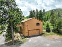 Side exterior featuring a garage and deck with stairs at 31150 Manitoba Dr, Evergreen, CO 80439
