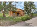 Charming home with a rear patio, wood siding, and access to the outdoors via stairs at 31150 Manitoba Dr, Evergreen, CO 80439