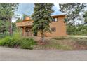 Exterior view of a home with a wooden deck and stairs, surrounded by trees at 31150 Manitoba Dr, Evergreen, CO 80439