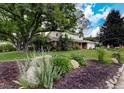 Beautifully landscaped front yard with a large shade tree and brick accents on this two-story home at 10373 W 75Th Ave, Arvada, CO 80005