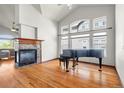 Bright living room featuring hardwood floors, a fireplace, high ceilings, and a piano at 1513 Cannon Mountain Dr, Longmont, CO 80503