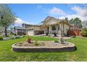 Landscaped front yard with a decorative stone retaining wall and beautiful green grass under a sunny sky at 107 Prairie Falcon Pkwy, Brighton, CO 80601