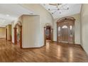 Elegant foyer with gleaming hardwood floors, arched doorways, and a stunning wood front door with glass accents at 14581 E Oberlin Pl, Aurora, CO 80014