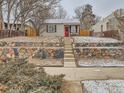 Charming home featuring a red front door and stone retaining wall and landscaped front yard with some snow at 3440 N Steele St, Denver, CO 80205