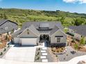 Aerial view of a modern home with a landscaped front yard and long driveway, set against a backdrop of rolling hills at 5225 Mesa Top Dr, Monument, CO 80132