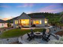 Beautiful backyard with a stone fire pit and seating area, a covered patio, and a well-manicured lawn at 5225 Mesa Top Dr, Monument, CO 80132